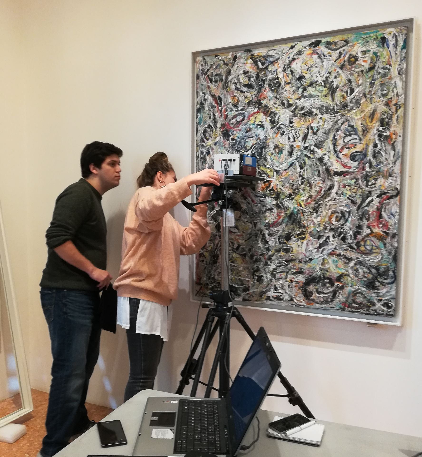 two people using equipment to evaluate painting