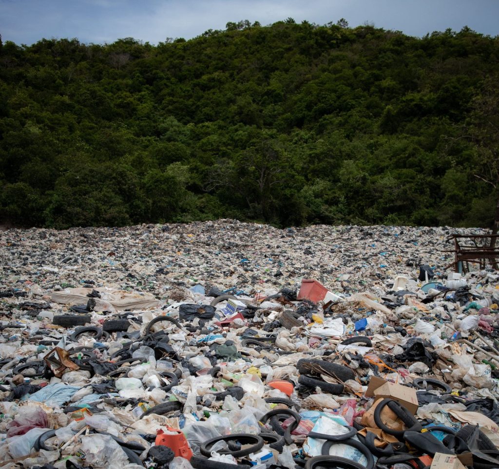 A landfill in front of trees, full of plastics -- including non-recyclable polyurethanes